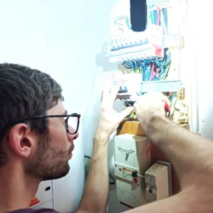 Photo de l'électricien qui met au norme un tableau électrique.